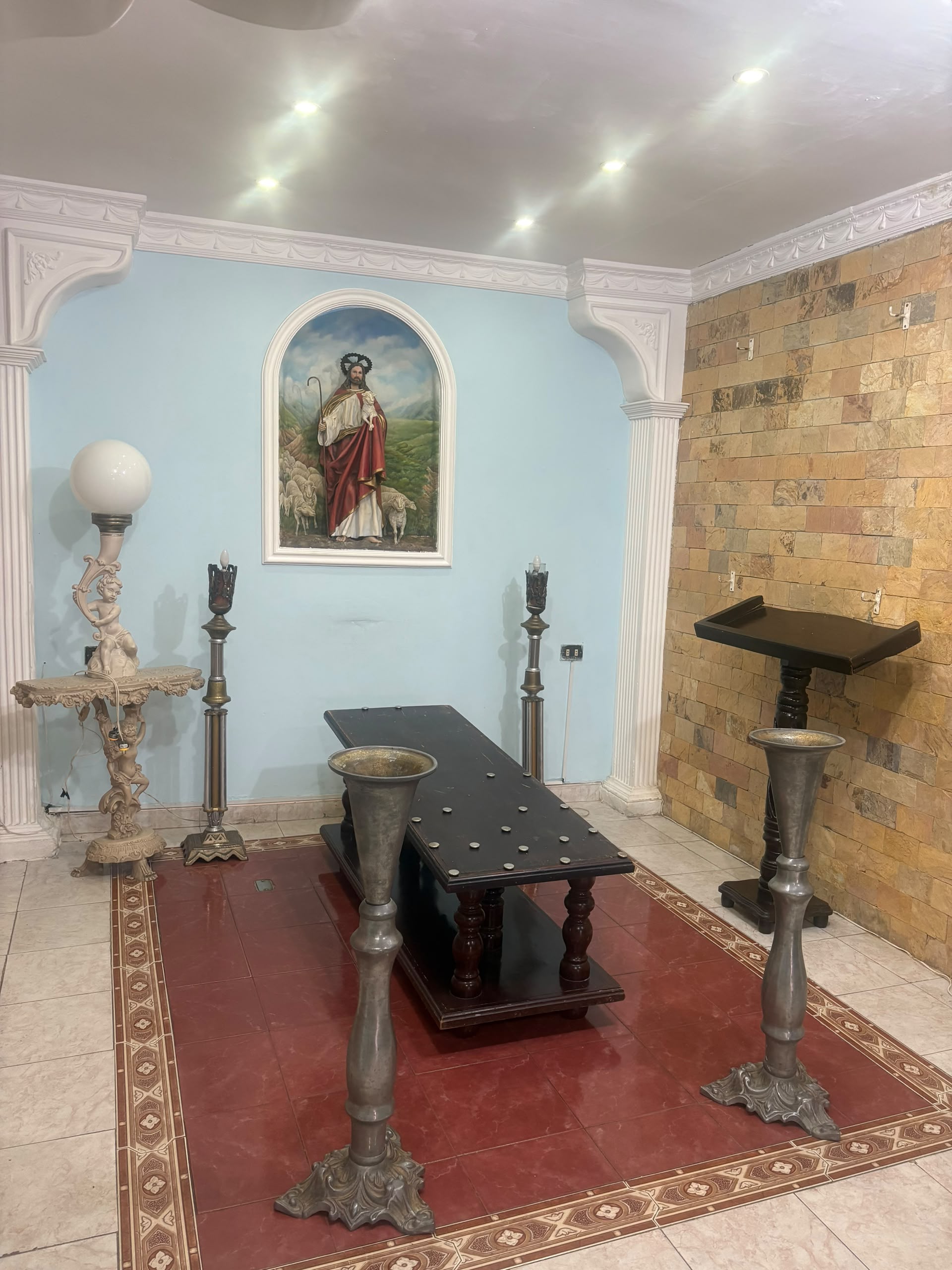 Sala velatoria con imagen del Buen Pastor y mesa para féretro