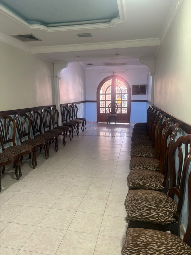 Sala velatoria extensa con sillas a ambos lados y vitral colorido al fondo